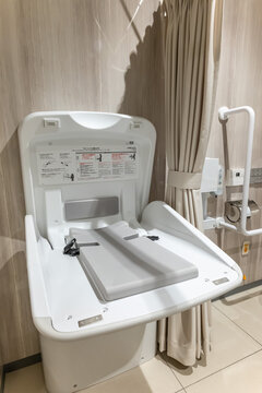 多目的トイレに設置された開閉式のおむつ交換台とプライバシー保護用のカーテン
