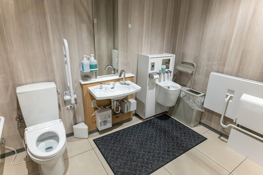 手すりやオストメイト対応設備を備えた清潔で広々とした多目的トイレのインテリア
