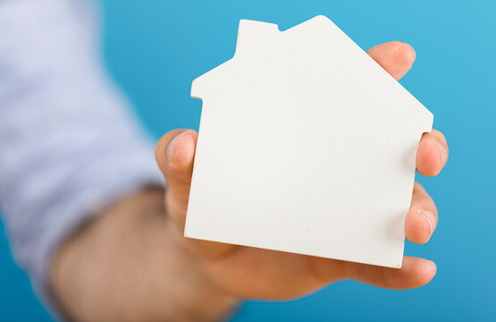 Hand holding a house shape, representing real estate, home ownership, and concepts of security. Perf