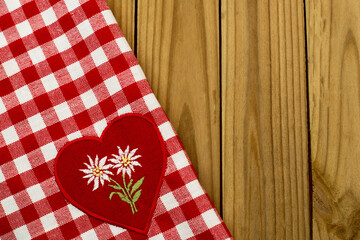 Obraz premium Checkered tablecloth with heart patch featuring flowers on wooden surface during a casual dining setting