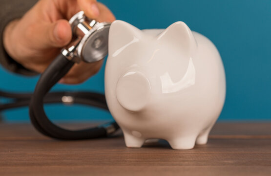 Checking savings and financial health. Piggy bank getting a medical checkup with a stethoscope. Inve