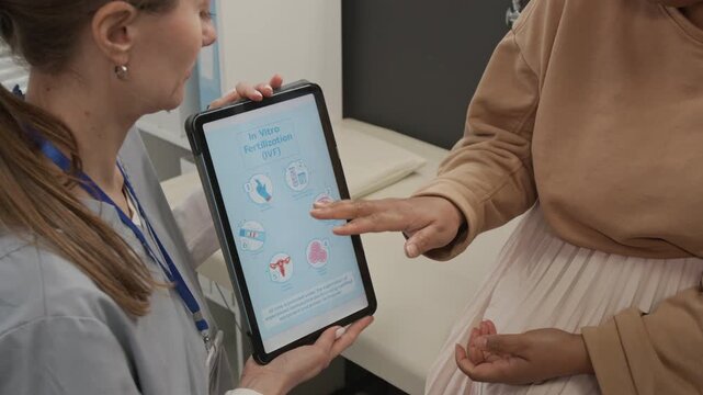 Midsection shot of unrecognisable Black patient discussing IVF procedure with Caucasian fertility expert holding digital tablet