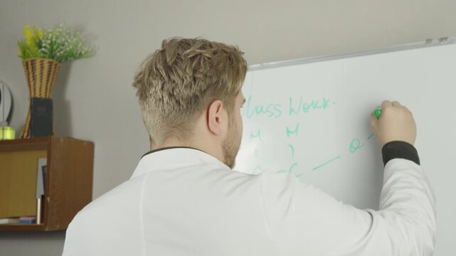 Male scientist or doctor writing formulas on whiteboard