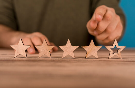 Person pointing at a four-star rating, customer satisfaction concept.