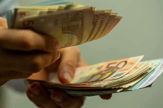 Close-up of hands meticulously counting a fan of euro banknotes