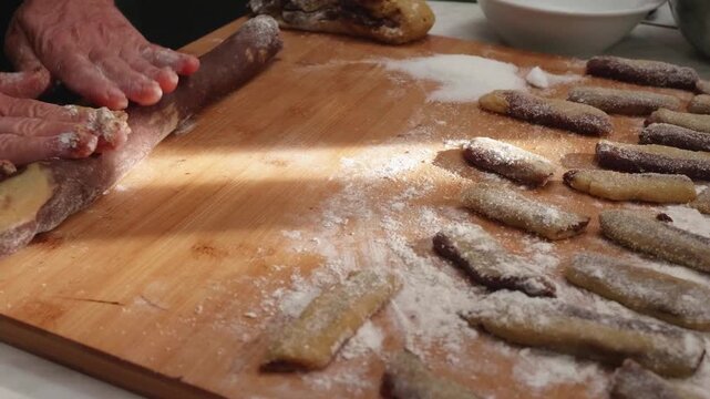 Woman hands shape cookie dough into individual forms. The manual process highlights creativity, care, and the handmade nature of baking.