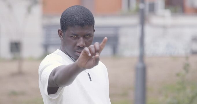 Young man in white shirt makes a strong no gesture with his finger, clearly expressing disagreement. The scene highlights refusal and clear communication.
