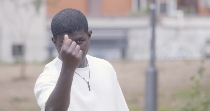 Young man in white shirt makes a money gesture with his hands, meaning that something requires payment. The scene conveys value and communication.