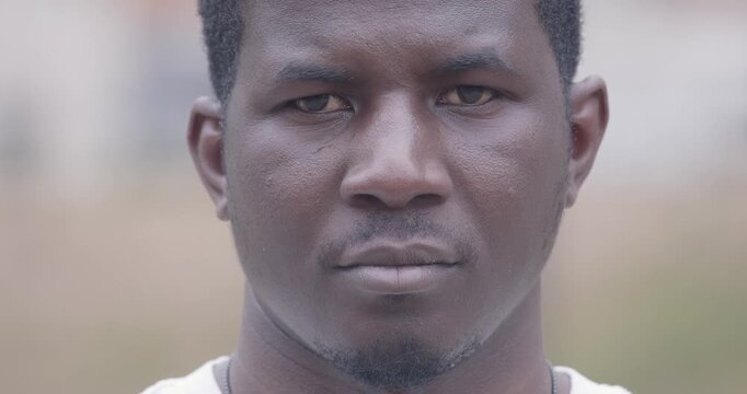 Extreme close-up of a young African man looking straight into the camera with a serious, proud expression. His gaze conveys confidence, strength, identity and self-awareness.