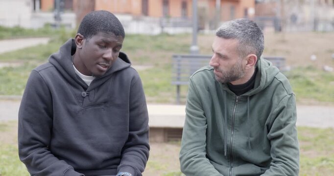 Two friends discuss personal and delicate topics in a park. The scene ends with a heartfelt embrace, showing mutual understanding, emotional connection and genuine support.