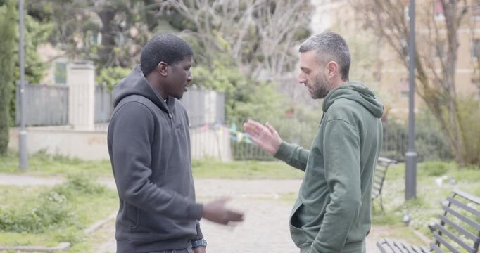 Two friends talk casually in a park before saying goodbye with a warm hug. They walk away in opposite directions, capturing a natural everyday farewell and strong friendship bond.