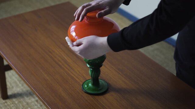 Hands clean a vintage table lamp before sale, ideal for antiques, resale, restoration, and home decor marketplace content.
