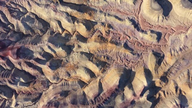 This abstract aerial perspective highlights the vibrant striated textures of the Painted Desert badlands. The unique geological patterns create an alien environment.