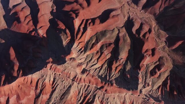 A zenith drone shot captures the surreal Painted Desert badlands. Vibrant earthy colors and unique sediment layers create a high-quality abstract nature background.