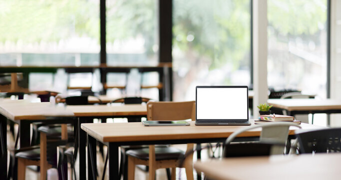 Photo of Contemporary Workspace White blank screen laptop on modern working desk. Equipment on table. Modern office concept. 