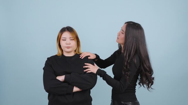 Young woman trying to hug and apologize to her offended friend