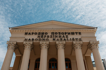 Fototapeta premium Low angle view of the National Theatre facade in Subotica, Serbia. Grand columns and historic design highlight cultural architecture.