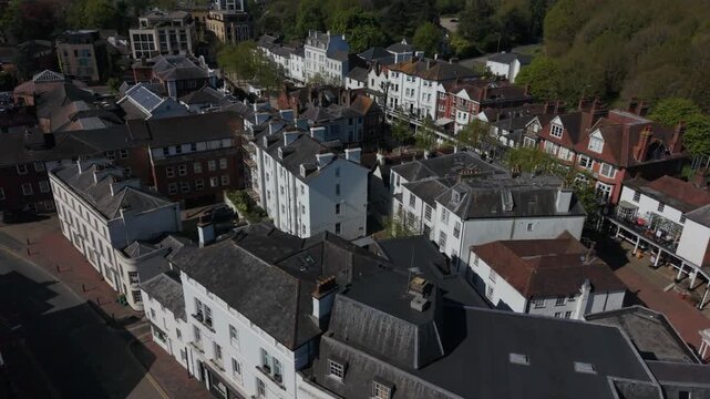 Flying above historic Pantiles in Royal Tunbridge Wells. Aerial view of tourist town with old buildings and town square. Popular street with restaurants, shops and a hotel with outdoor sitting.