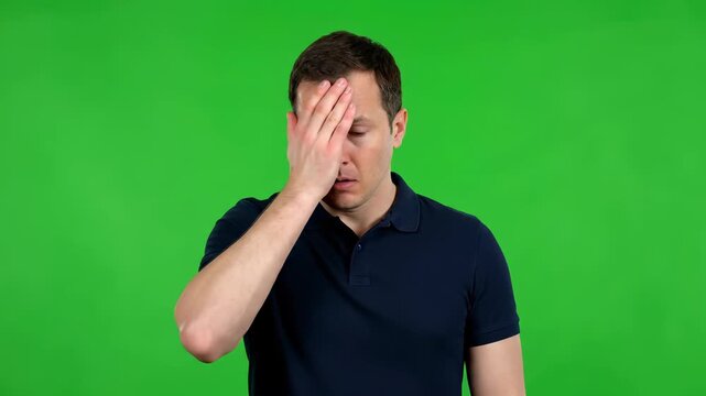 Frustrated Reflection: A man covers his face in a gesture of contemplation or worry, set against a vibrant green backdrop that amplifies the depth of emotion.