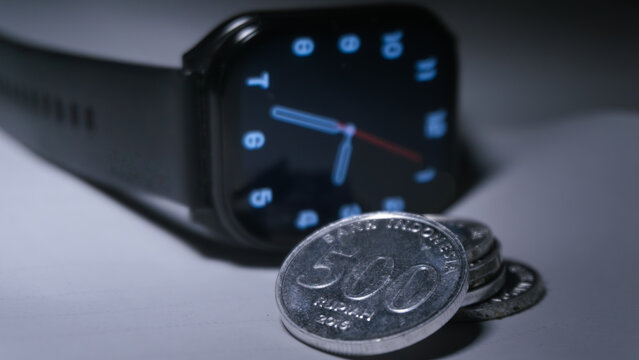 Digital smartwatch with Indonesian rupiah coins representing time and financial management