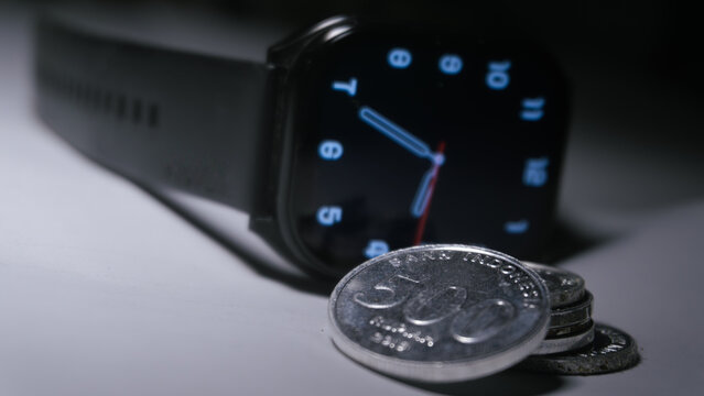 Digital smartwatch with Indonesian rupiah coins representing time and financial management