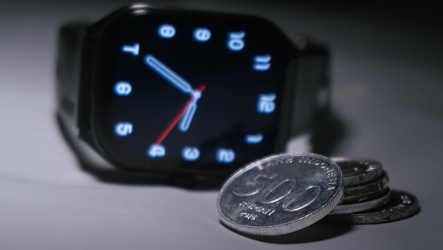 Digital smartwatch with Indonesian rupiah coins representing time and financial management