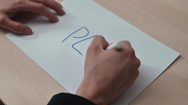 A person is writing the word plan on a piece of paper in four stages. The process shows close-up views of the writing as it evolves from initial sketches to final letters