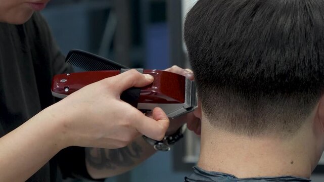 Professional barber trimming hair with electric clipper machine
