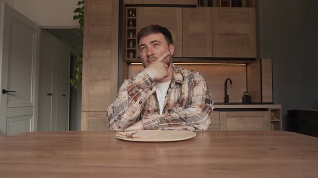 A man is sitting at the kitchen table and figuring out what kind of food to order.