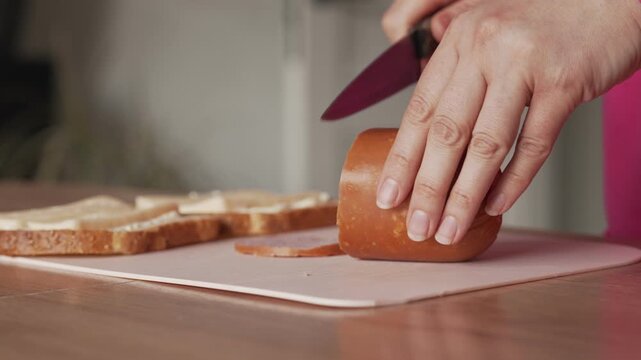 A housewife slices ham to make sandwiches. Cooking breakfast at home.