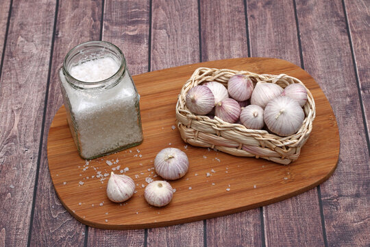 Solo garlic with sea salt on a rustic wooden board.
