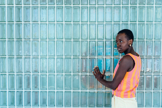 Neutral Black woman standing in minimalist interior with glass block wall