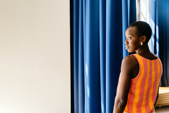 Black woman looking back in blue curtain interior with complementary colors