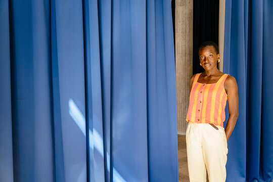 Neutral Black woman in blue curtain space with bold orange color contrast