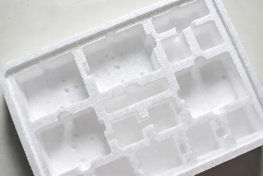 White styrofoam packaging insert with multiple compartments, abstract background, close-up
