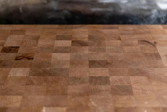 Close-up of a wooden butcher block countertop with a blurred dark background, natural texture