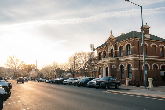 Historic brick building in regional NSW street lined with parked cars at sunset