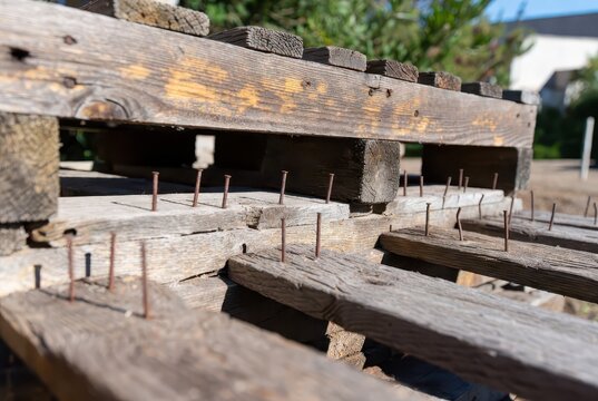 Rustic weathered wooden pallet with protruding rusty nails, outdoor setting