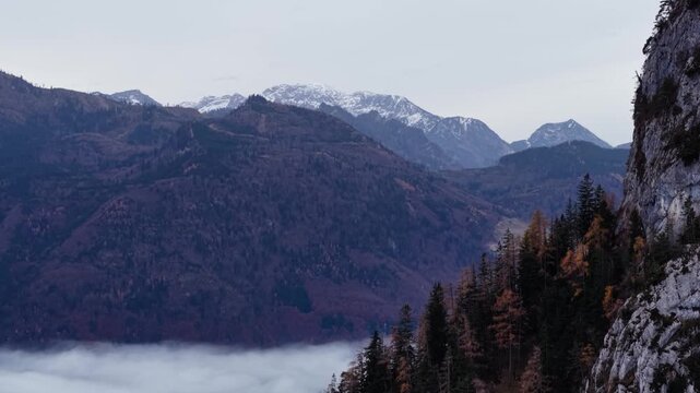 Aerial View of Steep Mountin Cliff and Distant SnowyPeaks in Autumn