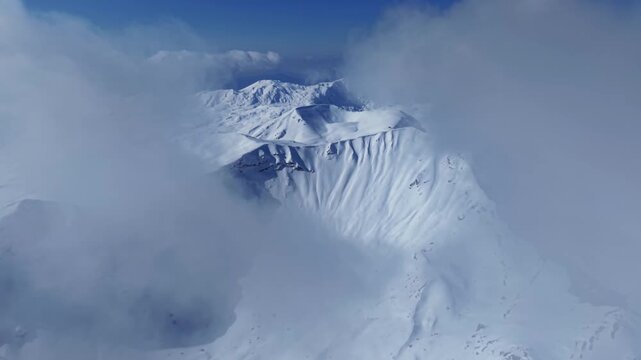 FPV Drone Shot Soaring Throgh Clouds Over Snow Covere Mountain Peak