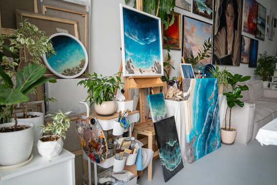 Creative working place at home art studio with wall exhibition, art supplies, epoxy art paintings, inspirational atmosphere for creating, professional workspace of craftsperson, indoor workshop.