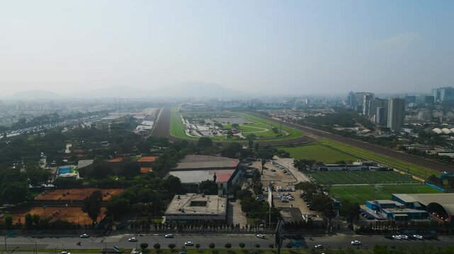 aerial view of the Monterrico horse racing track in Surco, 4K drone shot of the massive turf course and Lima urban landscape on a sunny autumn day.