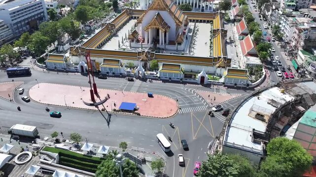 The red GiantSwing and wat suthat thepwararam temple appear within active city streets, historic architecture and movement around.