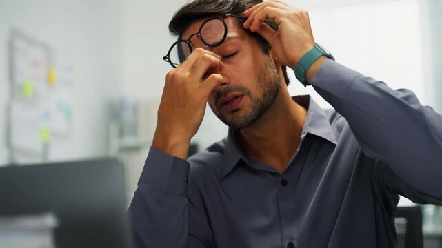 Man indoors, worried and upset, facing technology trouble and paperwork overload late into the night.