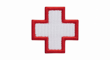 Obraz premium Embroidered red cross symbol on white fabric isolated on a plain white background surface