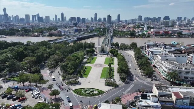 King Rama I Monument centered in landscaped park near river and bridge, stands within urban layout.