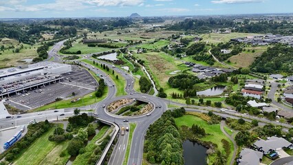 Aerial drone view of a roundabout intersection with a stream running through at Tauranga Crossing, Tauriko, New Zealand with Mount Maunganui in the background © Alice