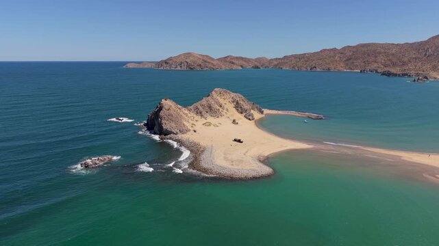 View the process of camping on a beach in Punta Final Bahia de Gonzaga with an SUV and teardrop camper trailer as waves crash nearby.