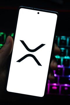 Punta Arenas, Chile &ndash; April 30, 2026: A person holding a smartphone displaying the Ripple (XRP) cryptocurrency logo on a white screen, with a colorful backlit gaming keyboard in the background