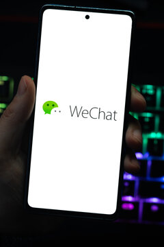 Punta Arenas, Chile &ndash; April 30, 2026: Close-up of a mobile phone screen showing the WeChat messaging app logo, held by a hand over a dark surface with glowing LED keyboard lights